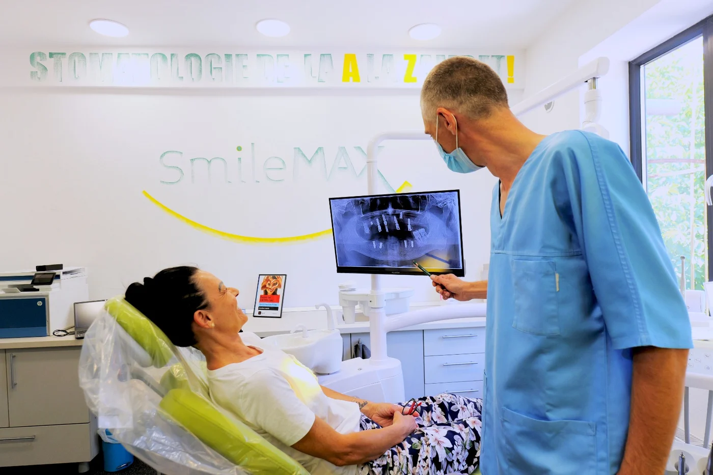 Medic stomatolog arătând unei paciente radiografia panoramică pe ecran, în cabinetul SmileMAX